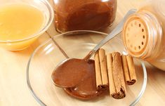 some cinnamon sticks are on a glass plate next to two jars with orange juice in them