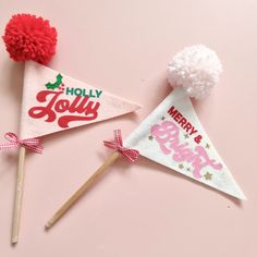 two christmas themed party hats on sticks with pom - poms