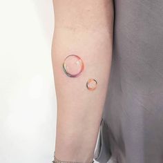 a woman's arm with a small water drop tattoo on the left inner arm