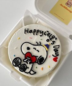 a birthday cake in a box with the words happy birthday snoopy and a cartoon character on it