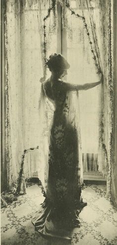 an old photo of a woman standing in front of a window with her arms outstretched