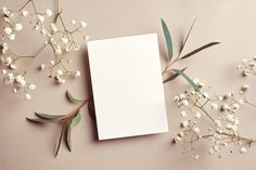 an empty card surrounded by white flowers and greenery on a pink background with space for text