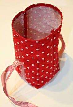 a red and white polka dot bag with a pink ribbon on the side, sitting on a table