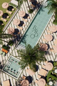 an aerial view of tables and chairs next to a swimming pool with palm trees in the foreground