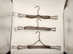 three metal clothes hangers on a white surface