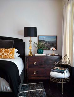 a bedroom with black and white bedding, gold accents and a painting on the wall