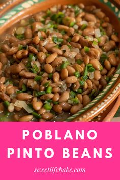 a bowl filled with beans and green onions on top of a wooden table next to a pink