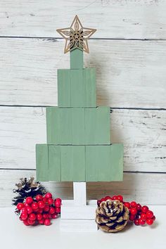 a christmas tree made out of wooden blocks with pine cones and berries on the side