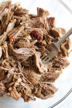 a glass bowl filled with shredded meat and cranberry sauce next to a fork