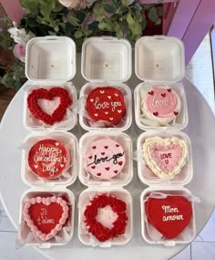 valentine's day treats are arranged in plastic containers on a white table with pink flowers