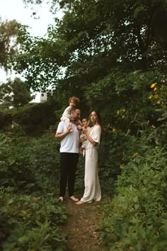 a man and two women standing in the middle of a forest with their arms around each other