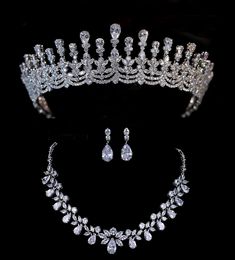 a tiara and earrings are shown on a black background in this image, there is also a necklace and earring set