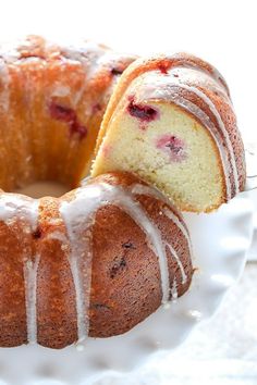 a bundt cake with white icing and cranberry toppings on a plate