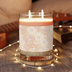 a lit candle sitting on top of a table next to some books and a guitar