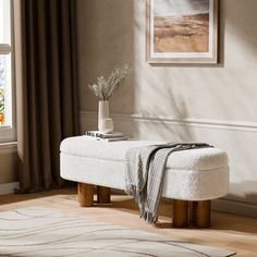 a white bench sitting in front of a window next to a rug and potted plant