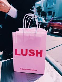 a person sitting at a table with a pink bag in front of them that says lush