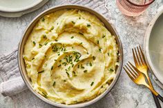 a bowl filled with mashed potatoes on top of a table next to silverware