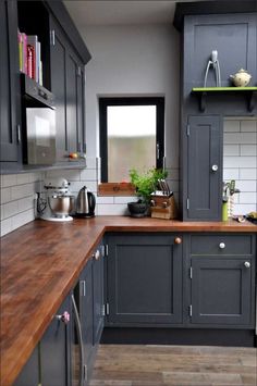 a kitchen with gray cabinets and wooden counter tops