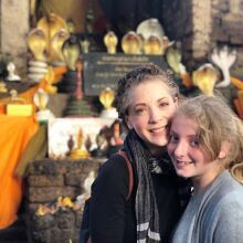 two young women standing next to each other in front of a display of gold items