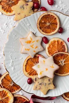 orange slices and star cookies on a plate with cranberries around them, surrounded by christmas decorations