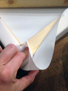 a person is holding a piece of paper and cutting it with a plane shaped object