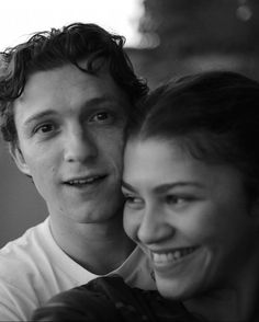 a young man and woman are smiling for the camera, black and white photo with focus on their faces