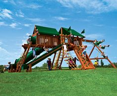 children playing on a wooden play set in the grass with blue sky behind it and green roof