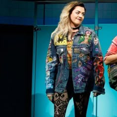 two women standing next to each other in front of a blue wall wearing colorful clothing