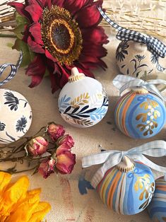 several decorated eggs sitting on top of a table next to a sunflower and ribbon