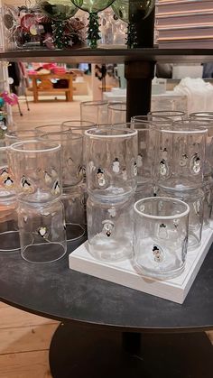 many glasses are sitting on a table in front of a glass shelf with other items