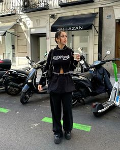 a woman standing in front of parked scooters and mopeds on the street