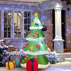 an inflatable christmas tree with presents on the ground and snow falling around it