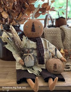 a scarecrow doll sitting on top of a wooden table next to a pumpkin and corn cob