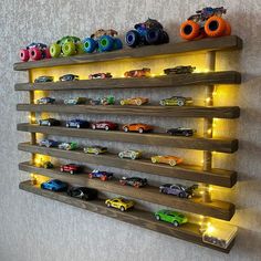 a wall mounted shelf filled with lots of toy cars on it's sides and lights around the shelves