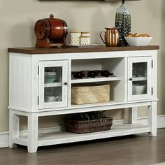 a white cabinet with glass doors and baskets on the bottom shelf in front of a beige wall