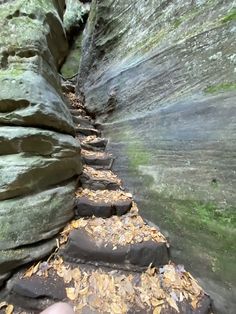 a person is standing on the side of a narrow path between two large rock formations