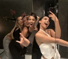 a group of women taking a selfie in front of a mirror