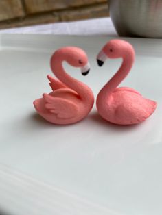 two pink flamingos sitting on top of a white table