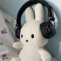 a white stuffed rabbit with headphones on it's ears sitting on a bed