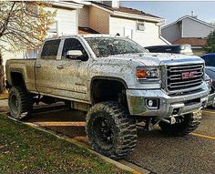 the truck is covered in mud and parked on the side of the road near some houses