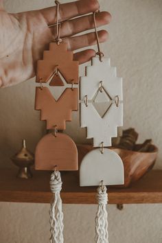 a person holding up some earrings on top of a wooden shelf next to other items