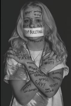 a woman with her arms crossed and words painted on her face in front of her