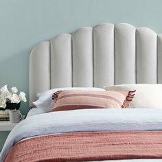 a bed with a white headboard and two pillows on it, next to a nightstand