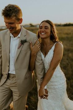 a bride and groom are walking through the grass