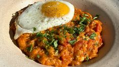 an egg is sitting on top of some food in a white bowl with parsley