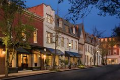 a street lined with tall buildings and trees in the evening time, at dusk or dawn