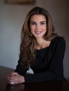 a woman sitting at a table smiling for the camera