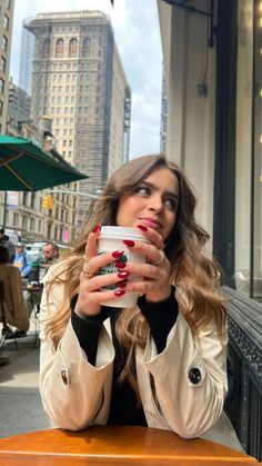 a woman sitting at a table with a cup of coffee