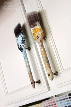 two paintbrushes are hanging on the door handles