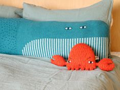 an orange stuffed animal laying on top of a bed next to a blue and white pillow